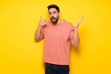 Telefon jest yapma ve şüphe sarı duvarın üzerinden yakışıklı adam