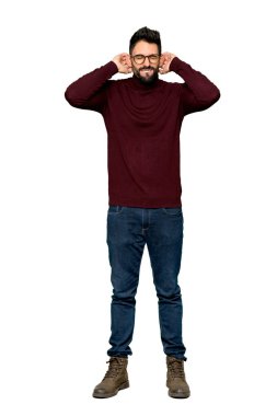 Yakışıklı adam gözlüklü elleriyle kulaklarını kapsayan tam uzunlukta bir kadeh. Hayal kırıklığı ifade izole beyaz arka plan üzerinde