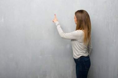 Dokulu duvar geri işaret parmağı ile işaret eden genç kadın