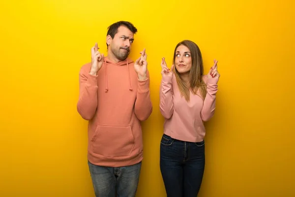 Groep Van Twee Mensen Gele Achtergrond Met Vingers Oversteken Wens — Stockfoto