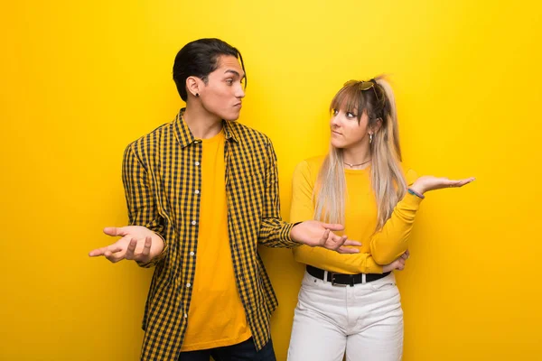 Junges Paar Vor Leuchtend Gelbem Hintergrund Mit Zweifeln Während Hände — Stockfoto