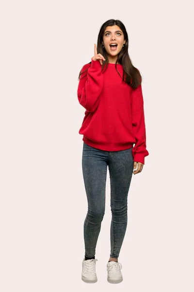 孤立した背景の上指を指してアイデアを考えて赤のセーターとティーンエイ ジャーの女の子のフルレングス ショット — ストック写真