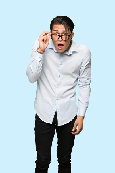 Bonito Homem Com Óculos Surpreso Com Fundo Azul Isolado — Fotografia de Stock