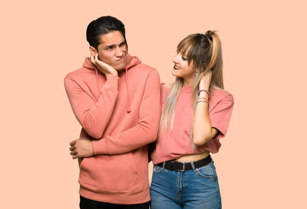 Young couple thinking an idea while scratching head over pink background