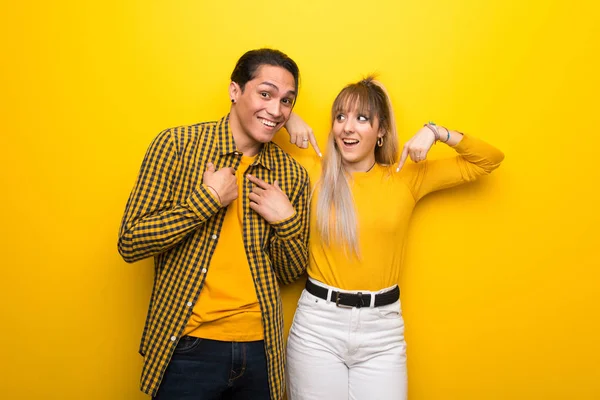 Sürpriz yüz ifadesi ile canlı sarı arka plan üzerinde genç çift