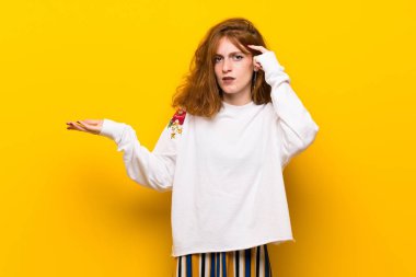 Sarı duvar parmak kafasına koyarak delilik jest yapma genç Kızıl saçlı kadın