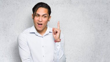 Yakışıklı adam dokulu duvar arka plan üzerinde parmak işaret bir fikir düşünme