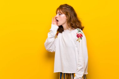 Sarı duvar bağırmak için lateral açık ağızlı genç Kızıl saçlı kadın