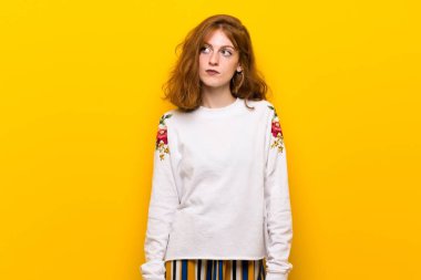 Sarı duvar ile ciddi bir yüz ararken genç Kızıl saçlı kadın