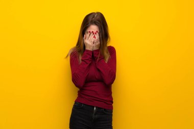 Kadın yorgun ve hasta ifade ile sarı duvarın üzerinden balıkçı yaka ile