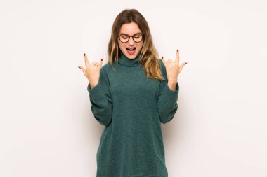 Genç kız rock jest yapma beyaz duvar üzerinde