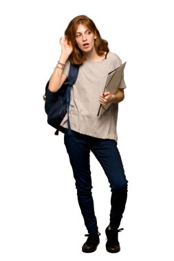Bir şey izole beyaz arka plan üzerinde kulak el koyarak dinleme genç redhead öğrenci tam uzunlukta bir kadeh