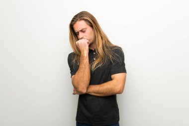 Beyaz duvar şüpheleri üzerinden uzun saçlı sarışın adam