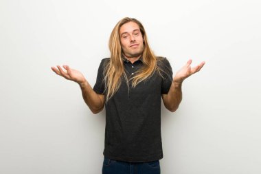 Omuz kaldırma sırasında önemli jest yapma beyaz duvarın üzerinden uzun saçlı sarışın adam