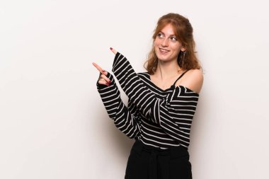 İşaret parmağı ile işaret ve ararken beyaz duvar genç Kızıl saçlı kadın