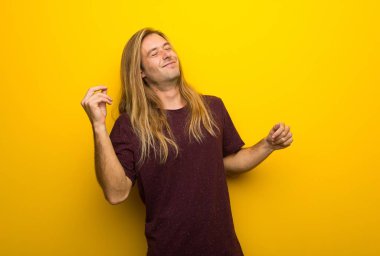 Sarı duvarın üzerinden uzun saçlı sarışın adam zevk müzik bir partide dans