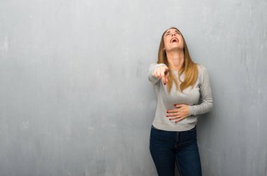 Birisi parmak ile işaret ve çok gülüyor dokulu duvar genç kadın