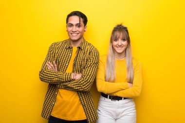 Canlı sarı arka plan üzerinde genç çift ön konumda çapraz kollarını tutarak