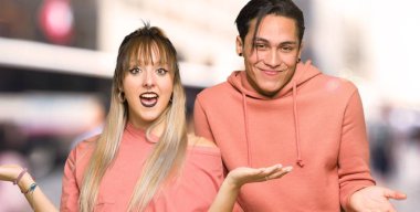 Şehirde omuz kaldırırken önemsiz jest yapan genç çift