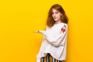 Sarı duvar görünümlü doğru gülümseyen iken bir fikir sunmak genç Kızıl saçlı kadın