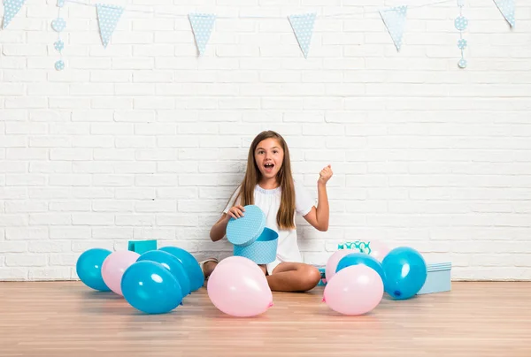 stock image Little girl in a birthday party opening a gift and making surprise gesture