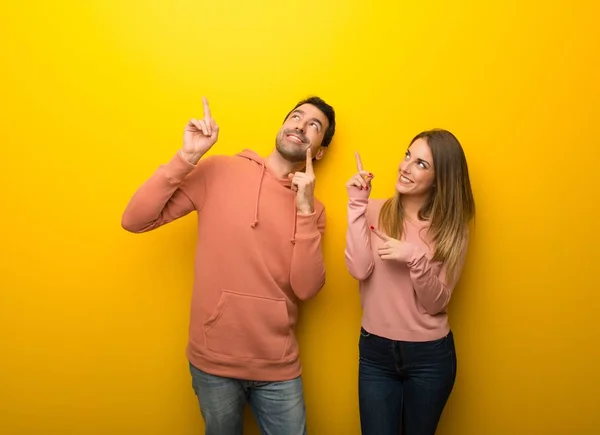 Група Двох Людей Жовтому Тлі Вказує Індексний Палець Дивиться Вгору — стокове фото