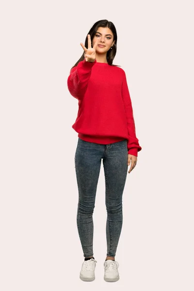 分離の背景の上の指を使って赤いセーター幸せとカウント 代の女の子のフルレングス ショット — ストック写真