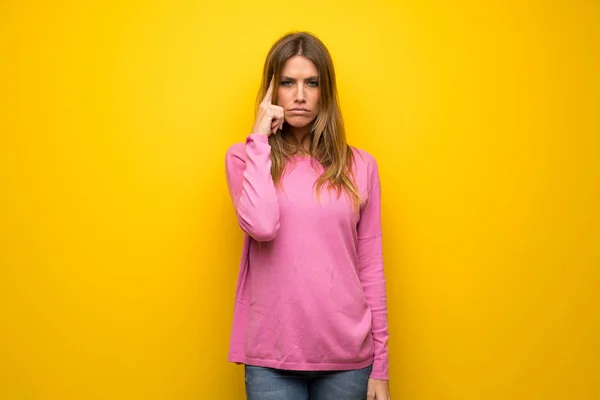 疑問を持つと考えて黄色の壁にピンクのセーターの女性 — ストック写真