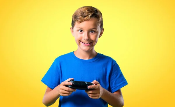 Niño Tocando Consola Sobre Fondo Amarillo —  Fotos de Stock