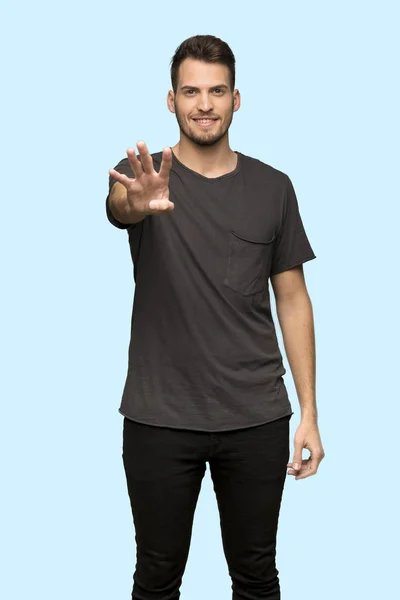 穿黑色衬衫的人高兴地数着四个手指在蓝色背景上 — 图库照片