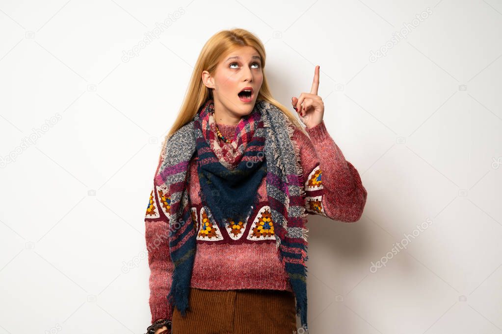 Hippie woman over white wall intending to realizes the solution while lifting a finger up