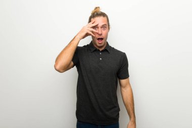 Sürpriz ve şok yüz ifadesi ile beyaz duvarın üzerinden uzun saçlı sarışın adam