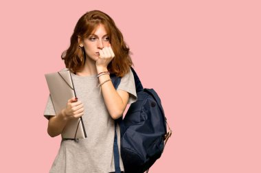 Pembe arka plan üzerinde şüpheleri genç redhead öğrenci