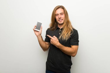 Belgili tanımlık hareket eden gösterilen beyaz duvarın üzerinden uzun saçlı sarışın adam