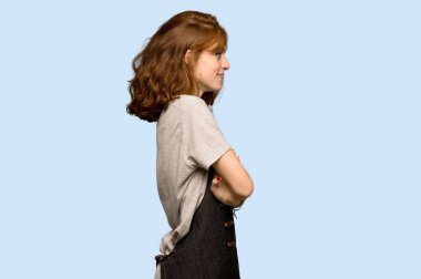 Önlük mavi arka plan üzerinde lateral pozisyonda olan genç Kızıl saçlı kadın