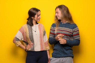 Hippi çift silah, kalça ile poz ve gülümseyen sarı arka plan üzerinde