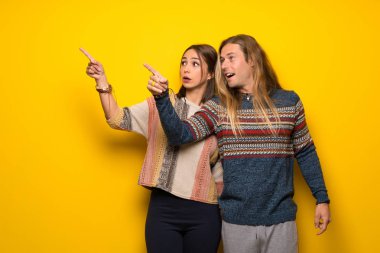 Hippi çift uzağa işaret eden sarı arka plan üzerinde