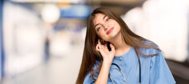 Genç hemşire için bir şey üzerinde bir hastane kulağına el koyarak dinleme