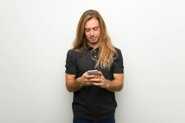 Beyaz duvar mobil ileti gönderme üzerinde uzun saçlı sarışın adam