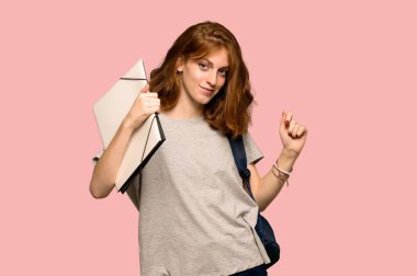 Genç redhead öğrenci zevk pembe arka plan üzerinde bir partide müzik dinlerken dans