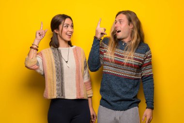 Hippi çift sarı arka plan niyetinde üzerinde parmak kaldırma sırasında çözüm anlar