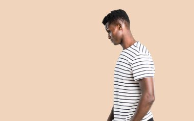 Koyu tenli adam ayakta ve izole koyu sarı arka plan üzerinde seyir çizgili gömlek ile