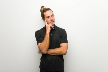 Beyaz duvar ararken bir fikir düşünce üzerinde uzun saçlı sarışın adam