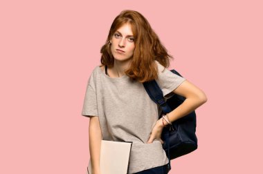 Genç redhead öğrenci için bir çaba pembe arka plan üzerinde yapılmış olan sırt ağrısı muzdarip