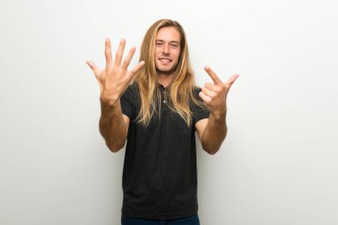 Beyaz duvar yedi parmak ile sayma üzerinde uzun saçlı sarışın adam
