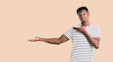 Sunulması ve izole koyu sarı zemin üzerine gelmek için davet çizgili gömlekli olan koyu tenli adam