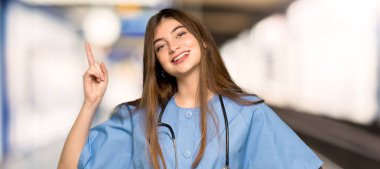 Genç hemşire gösterilen ve bir hastane en iyi işareti parmak kaldırma