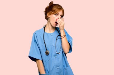 Esneme ve pembe arka plan üzerinde el ile geniş açık ağız kapsayan genç redhead hemşire