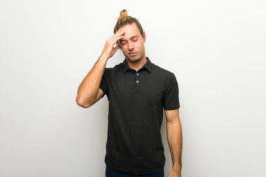 Yorgun ve hasta ifade ile beyaz duvarın üzerinden uzun saçlı sarışın adam