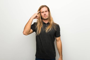 Beyaz duvar parmak kafasına koyarak delilik jesti yapım üzerinde uzun saçlı sarışın adam